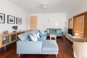 a living room with a blue couch and a tv at Six River - LJHooker Yamba in Yamba