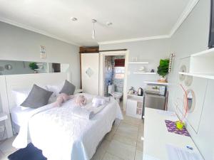 1 dormitorio con 1 cama blanca y cocina en Kwaaamiii, en Ciudad del Cabo