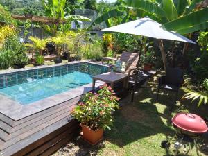 een achtertuin met een zwembad, een tafel en een parasol bij A Peace In Paradise in Baie Lazare Mahé