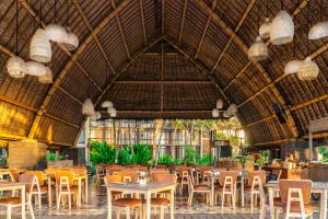 a restaurant with tables and chairs in a building at Wyndham Tamansari Jivva Resort Bali in Keramas