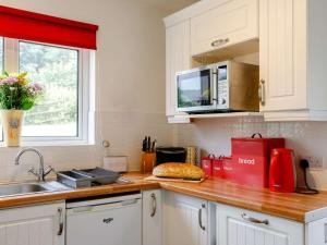 a kitchen with a counter with a sink and a microwave at 1 Bed in Ashford-in-the-Water 87471 in Great Longstone