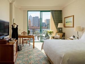 a hotel room with a bed and a desk and a television at The Langham Melbourne in Melbourne