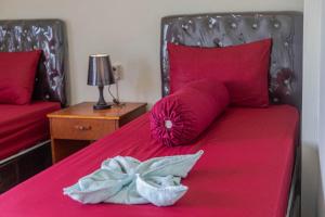Una cama con sábanas rojas y una almohada rosa con una flor en Teras Sawah Guest House Syariah, en Sembalun Lawang