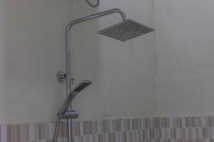 a shower head in a bathroom next to a wall at Teras Sawah Guest House Syariah in Sembalun Lawang