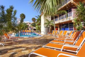 a group of orange lounge chairs next to a swimming pool at Ocean Beach Palace in Fort Lauderdale