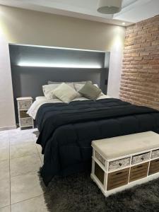 1 dormitorio con 1 cama grande y pared de ladrillo en Loft & Wines en Maipú