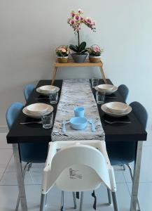 una mesa negra con sillas y una mesa con platos y cuencos en Greenfield Residence Sunway Subang 9Pax 3R2B with Internet, en Petaling Jaya