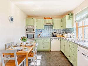 uma cozinha com armários verdes e uma mesa de madeira em 3 Bed in Ardvasar CA071 em Aird of Sleat