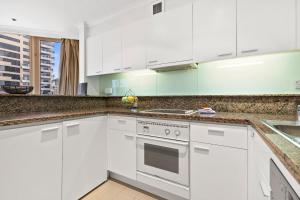 a white kitchen with white cabinets and a sink at Quay West 2302 Self-Catering in Sydney