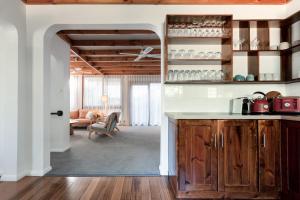 a kitchen with wooden cabinets and a living room at Thrower Cottage: Gateway to the Cataract Gorge in Royal Park