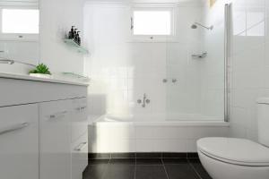 a white bathroom with a tub and a toilet at Thrower Cottage: Gateway to the Cataract Gorge in Royal Park +54 photos