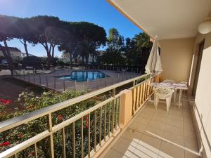 einen Balkon mit einem Tisch, einem Sonnenschirm und einem Pool in der Unterkunft Appartement Sainte-Maxime, 2 pièces, 4 personnes - FR-1-780-18 in Sainte-Maxime