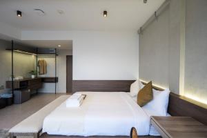 a bedroom with a large white bed and a bathroom at C'HOUSE Bangkok in Pom Prap