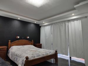 1 dormitorio con cama y pared negra en JE Leloir Apart en Neuquén