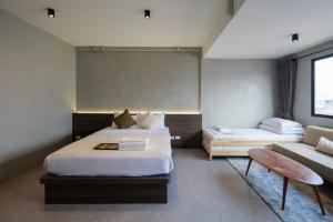 a hotel room with two beds and a couch at C'HOUSE Bangkok in Pom Prap