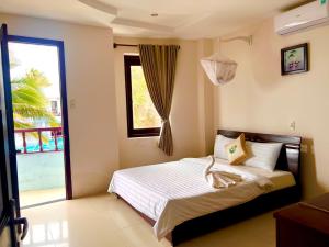 Schlafzimmer mit einem Bett und einem Fenster in der Unterkunft Sóng Biển Xanh Mũi Né Resort - by Bay Luxury in Ấp Long Sơn