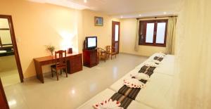 Zimmer mit 2 Betten, einem Tisch und einem TV in der Unterkunft Sóng Biển Xanh Mũi Né Resort - by Bay Luxury in Ấp Long Sơn