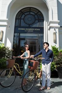 Shining Riverside Hoi An Boutique & Spa في هوي ان: رجل وامرأة يقفان بجوار دراجاتهما