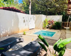 un patio trasero con piscina y sillas junto a una valla en Perro Loco Villas en Paraíso