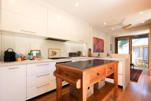a kitchen with white cabinets and a wooden island at Charming 3-Bedroom Terrace in the Heart of Glebe in Sydney
