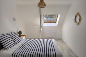 a bedroom with a bed with striped pillows and a window at Ty Kaouenn ARMOR in Plumergat