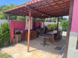 a patio with a wooden pergola and a table and bench at Casa em Porto, piscina e 5 qrts in Porto De Galinhas