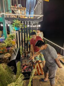 two men preparing food on a grill in a store at Hồ Mây Homestay in Bảo Lâm