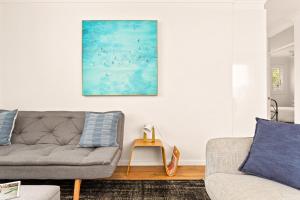 a living room with a couch and a painting on the wall at Chic apartment footsteps from Manly Beach in Sydney