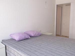 zwei lila Kissen auf einem Bett in einem Schlafzimmer in der Unterkunft Appartement 3 pièces avec terrasse, clim, wifi, garage en centre-ville à Sainte-Maxime - FR-1-780-57 in Sainte-Maxime