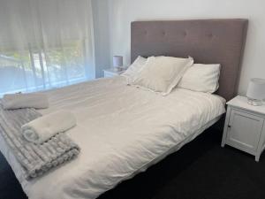 a large bed with white sheets and pillows on it at 3 Bedroom Home in Cheltenham in Cheltenham