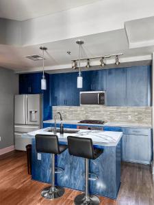 una cocina con armarios azules, fregadero y 2 taburetes en Highrise the Heart of Downtown, en Phoenix