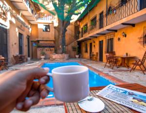 a person holding a coffee cup in front of a pool at Boutique Hotel Colonial in Santo Domingo