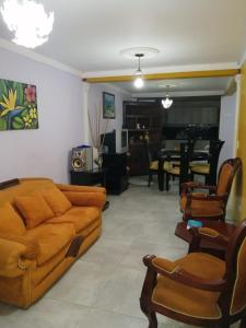 ein Wohnzimmer mit einem orangenen Sofa und Stühlen in der Unterkunft Hostal Kuyay in Filandia