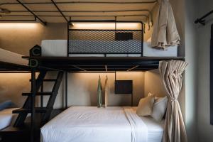 a bedroom with a bunk bed with white sheets at C'HOUSE Bangkok in Pom Prap