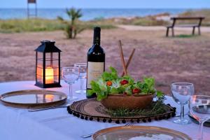 - une table avec une bouteille de vin et un bol de salade dans l'établissement Maison de 2 chambres a Poggio Mezzana a 100 m de la plage avec terrasse et wifi, à Poggio-Mezzana