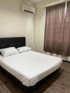 a bedroom with a bed with white sheets and a window at 1717 Bintulu Homestay 1 in Bintulu