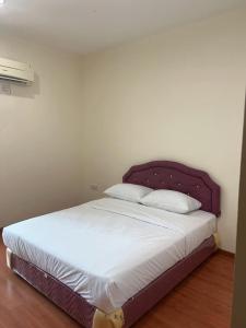 - un lit avec une tête de lit violette dans une chambre dans l'établissement 1717 Bintulu Homestay 1, à Bintulu