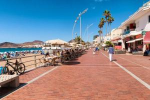 people walking down a sidewalk near the beach at 2 bedrooms appartement with wifi at Las Palmas de Gran Canaria in Las Palmas de Gran Canaria