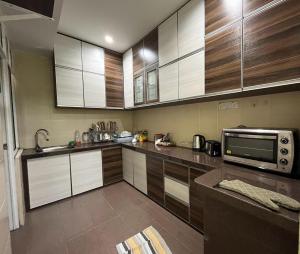 cocina con armarios de madera y microondas en Mega Homestay, en Butterworth