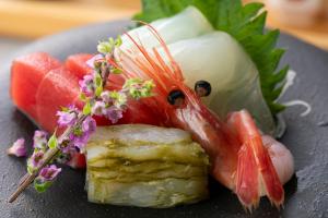 KAMENOI HOTEL Fukui في فوكوي: صحن طعام فيه سمك وبطيخ