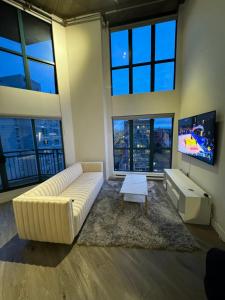 a living room with a large couch and a tv at LUXURY LOFT IN DOWNTOWN VANCOUVER in Vancouver