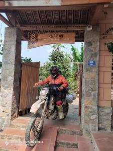 Un uomo che cavalca una moto da cross fuori da un cancello di Kha Bản Homestay a Cao Bằng