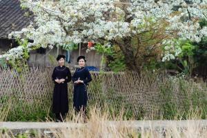 twee vrouwen die voor een bloeiende boom staan bij Kha Bản Homestay in Cao Bằng