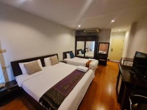 a large bedroom with two beds and a television at Kiatthada Resort in Bangkok