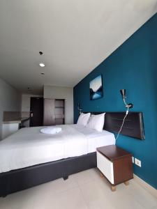 een slaapkamer met een groot bed met een blauwe muur bij izicozi Hotel Jababeka in Cibeber