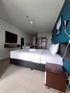 een slaapkamer met een groot bed en een televisie bij izicozi Hotel Jababeka in Cibeber