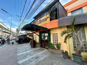 ein Gebäude mit einer Palme neben einer Straße in der Unterkunft Elegance Guesthouse in Manila
