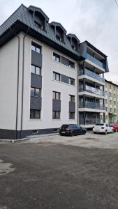a large white building with cars parked in a parking lot at Scandinavia Mountain View Apartment in Piatra Neamţ