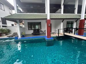 a swimming pool in front of a house at Amara Beach Resort Koh Phangan in Haad Yao