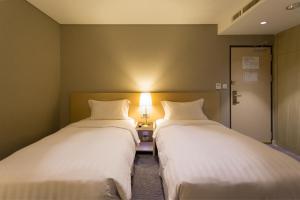 高雄的住宿－麗馨商旅七賢館，两张床位于带灯的房间。